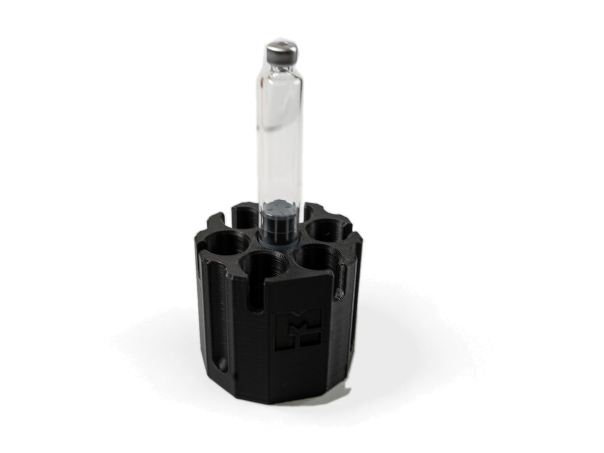 One 3 mL glass cartridge standing on the center purge post of the MODTECH purge station