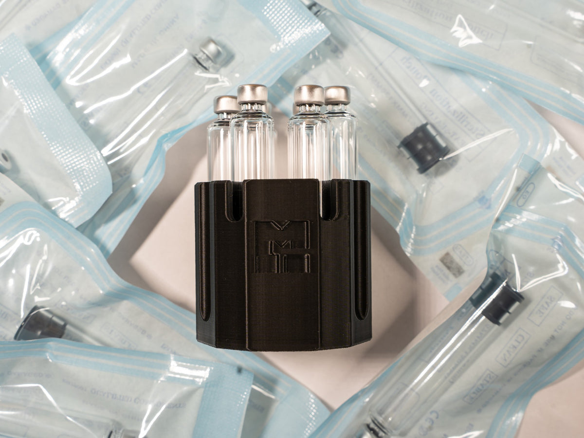 MODTECH purge station holding 3 mL cartridges, set on a pile of cartridges sealed in their sterilization pouches