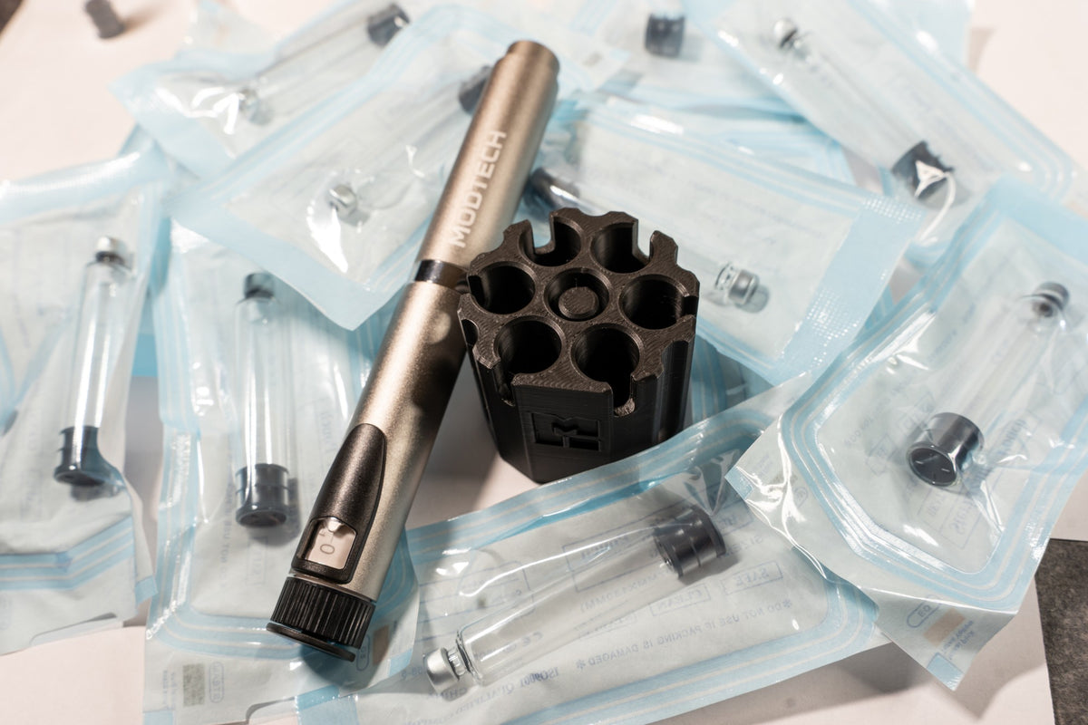 Silver MODTECH V2 pen beside the purge station seen from above: six slots around the center purge post, on sealed 3 mL cartridge pouches